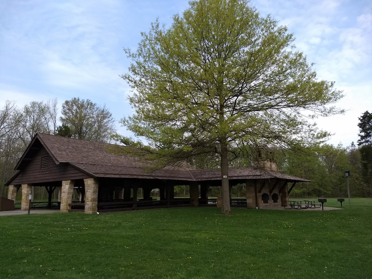 A picture of the Oak Grove Picnic Area, a brown shelter surrounded by woods and a big, open field.